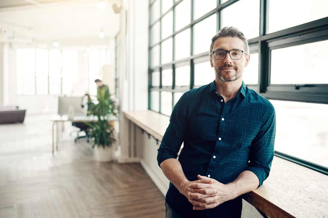 Portrait of a property operations director leaning on a window ledge in a bright office